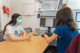 Student sitting at a desk with mentor and professor