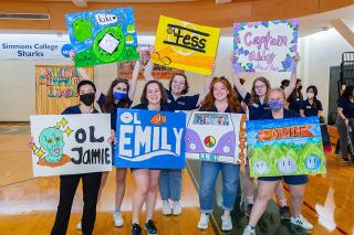 Students holding various signs on the Simmons basketball court