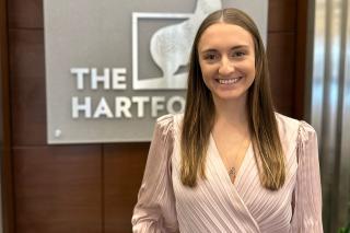 Photo of Abigail Willis in front of a sign for "The Hardford"