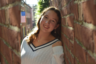 Anna Kelly leaning against a brick wall and smiling