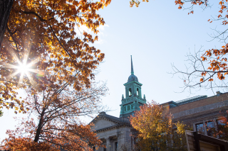 The cupola of the Main College Building on the Simmons University campus, as seen through a tree with colorful fall leaves