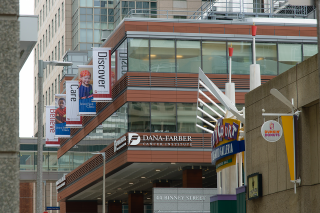 A view of the Dana Farber Cancer Institute from the street, with baners on the building that say "Believe", "Care", and "Discover"