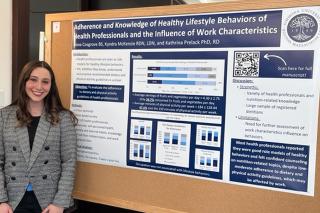 Nutrition Student Alexa Cosgrove in front of bulletin Board for project