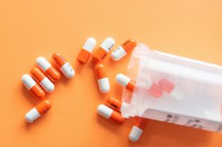 A number of pills pouring out of a prescription bottle.