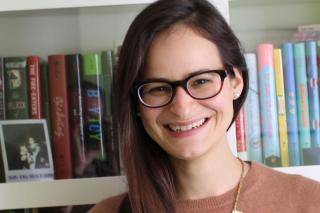 Rotem Moscovich standing in front of a shelf full of books