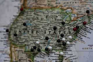 A close up of the United States on a globe with a variety of push pins marking different locations