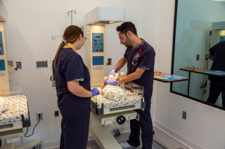 Two nursing students work with the infant simulator