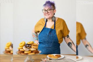 Corrie Locke-Hardy standing at a counter with a plate of donuts