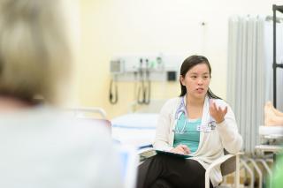 A nursing student seated in a chair and gesturing with her hand