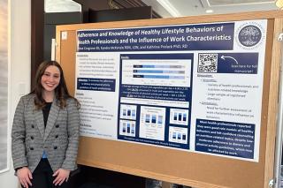Nutrition Student Alexa Cosgrove in front of bulletin Board for project