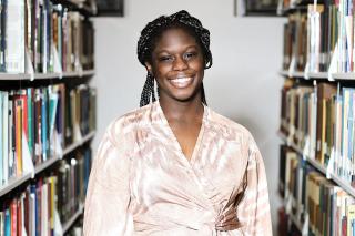 Kayla Pringle ’26 standing among the book stacks in the Simmons library