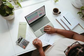 A student working at a desk with a laptop and a calculator. Photo by Microsoft 365 on Unsplash
