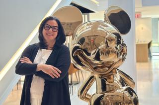 Christa N. Garubo ’91 stands next to a large golden statue of Mickey Mouse