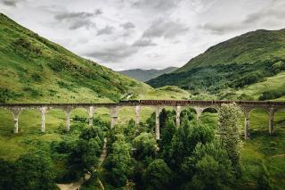 A train going over a long elevated bridge in Scotland. Photo by Bjorn Snelders on Unsplash.