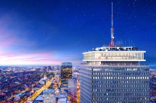 Photo of Prudential Building at night. Boston lit in the background
