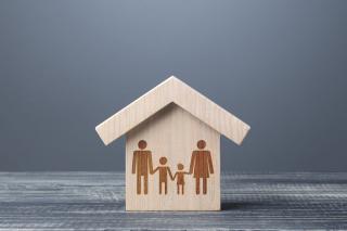A house cut out of wood with an etching of a family in the main part of the house