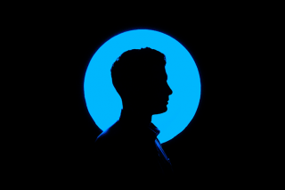silhouette of person in front of blue circle on a black background