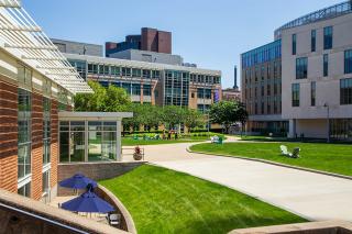 Photo of main campus quad on a bright sunny day. the view is looking from the Fens towards Drinan Hall and Palace Road