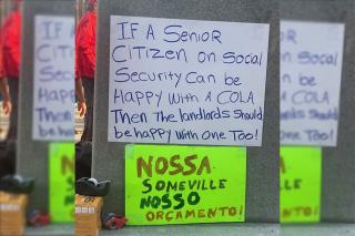 Signs from a rent control rally in Somerville, MA. The Brazilian Portuguese translates to "Our Somerville, our budget."