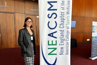 Zuzanna Misztela standing by a banner at the NEACSM Conference in 2025