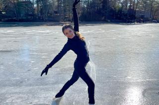 Arianna Joyce ’26, ’27MS standing in a pose on ice skates