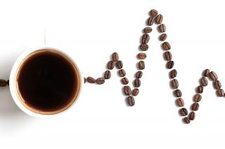 A cup of coffee on top of a line of coffee beans representing the line on a heart monitor