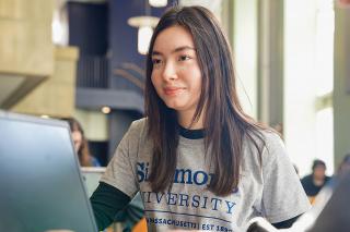 Student is Simmons t-shirt sitting at computer