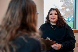 Person holding clipboard speaking to another person