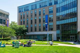 Students enjoying a summer day on the adirondack chairs outside of Drinan Hall on the Simmons University campus