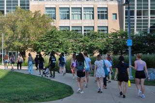 A group of people walking on the sidewalk of the Simmons campus