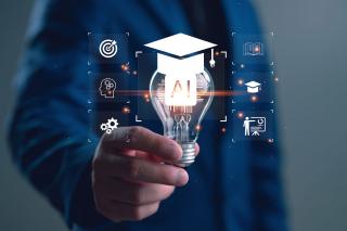 A graphic of a person holding a lightbulb with the letters "AI" on it and a graduation cap on top of it.