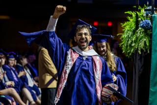 A graduate student pumping his fist in the air at Commencement 2026