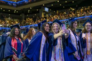 Two students taking a selfie during the 2026 Commencement ceremony for Simmons University 