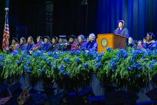 Lt. Governor Kim Driscol at the podium during the 2026 Simmons University Commencement ceremony. Simmons leadership and faculty are seated next to the podium. Photo credit: Joshua Qualls, Governor’s Press Office