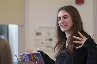 Student standing and speaking in front of class.