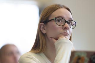 Student with glasses sitting and listening in classroom.