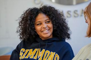 Simmons student smiling talking to another student