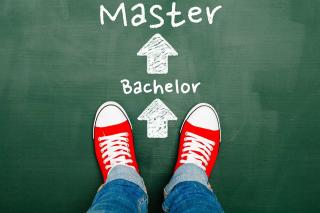 A graphic of feet standing on a chalkboard where the words bachelor and master are printed with arrows between them