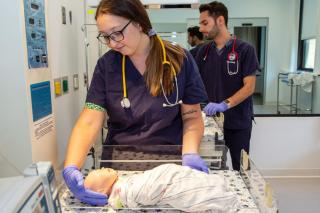Nursing student working in nursing simulation lab with model baby