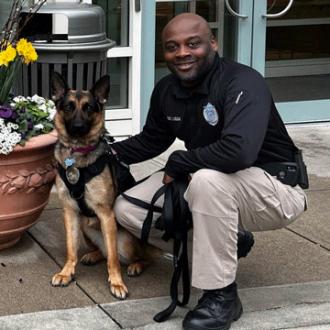 Athena, the Simmons Police comfort dog, with Detective Melvin Detective Ligon smiling for the camera