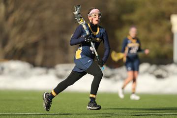 Student playing lacrosse at Daly Field