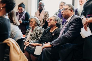 Attendees listening to speakers at the Ifill Stamp event