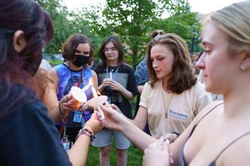 Students lighting each others' candles during the 2021 Candle Lighting Ceremony