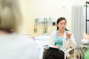 A nursing student seated in a chair and gesturing with her hand