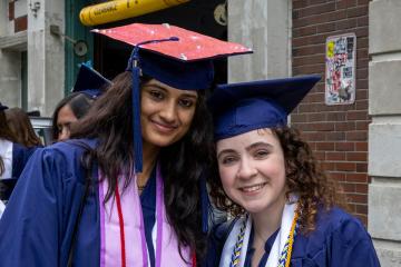 Two Simmons students in caps and gowns awaiting the start of the 2025 Commencement ceremony