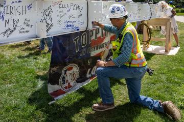 A member of the construction team signing the beam at the LLC Topping Off Ceremony