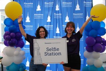 Orientaiton 2025 - Two students holding up a "Selfie Station" sign