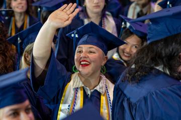 A graduating Simmons student offers a big wave during Commencement 2026. Photo credit: Natalya Lavrenov
