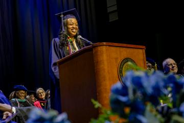 A student speaker smiles while addressing the audience at the 2026 Commencement ceremony. Photo credit: Natalya Lavrenov