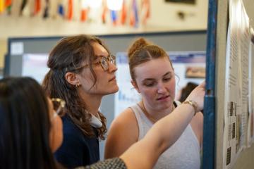 Students looking closely at a poster during the 2026 STEM Colloquium